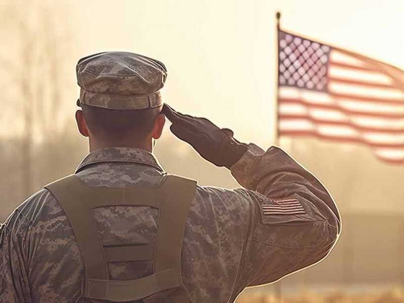 Military person saluting an American flag in the background