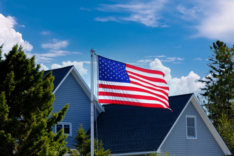 Military person saluting an American flag in the background